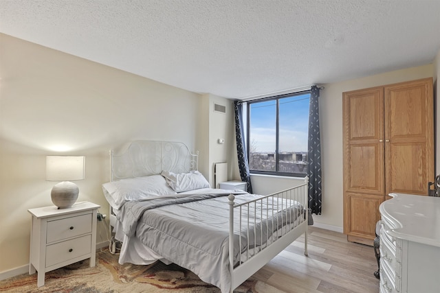 bedroom featuring light wood-type flooring and a textured ceiling