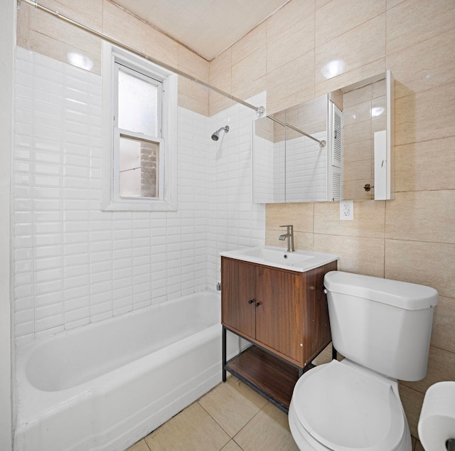 full bathroom with tile walls, tiled shower / bath combo, vanity, toilet, and tile patterned floors