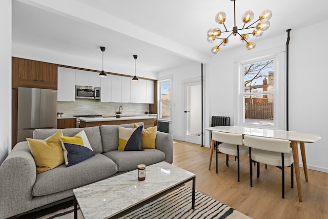 living room featuring sink, an inviting chandelier, and light hardwood / wood-style flooring