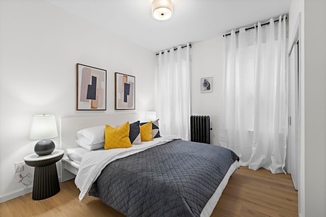 bedroom featuring hardwood / wood-style flooring and radiator heating unit