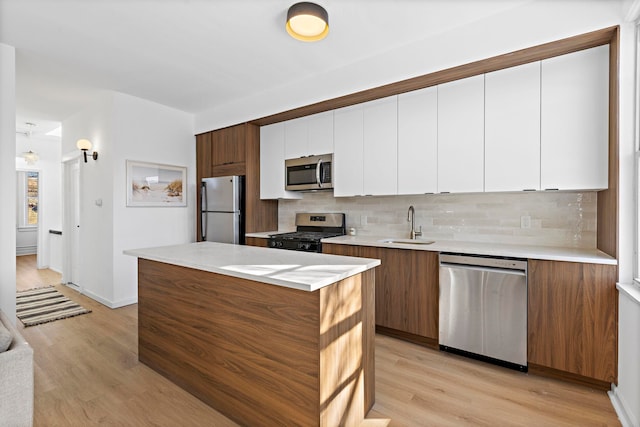 kitchen featuring white cabinetry, appliances with stainless steel finishes, backsplash, and light hardwood / wood-style floors