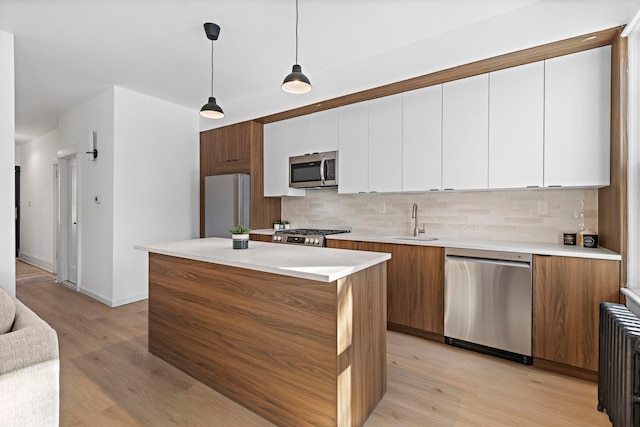 kitchen with white cabinetry, appliances with stainless steel finishes, sink, and pendant lighting