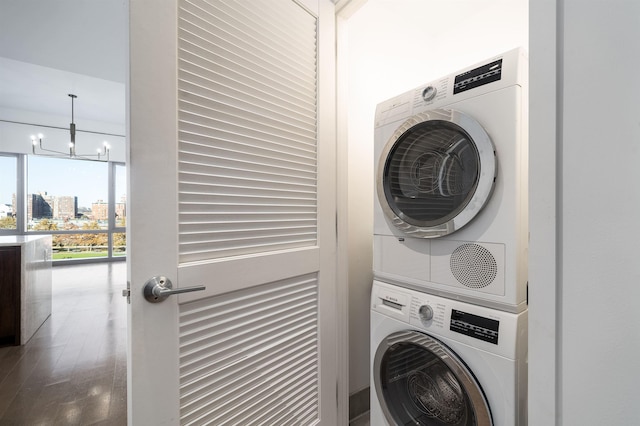 washroom featuring stacked washing maching and dryer and a chandelier