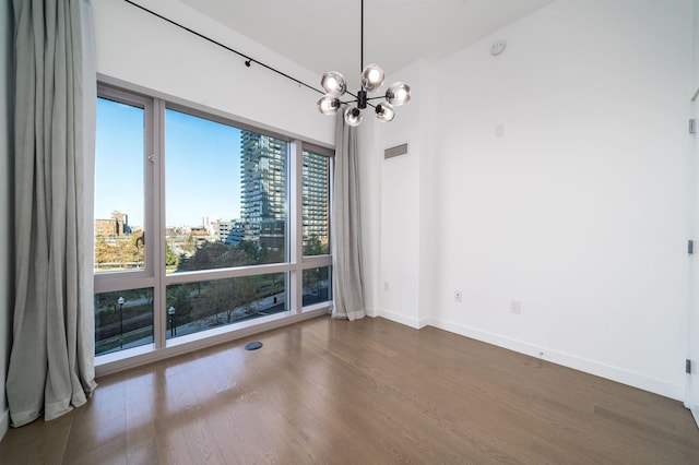 spare room with dark hardwood / wood-style flooring and a notable chandelier