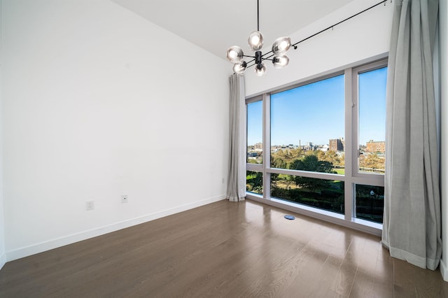 spare room with dark wood-type flooring and an inviting chandelier