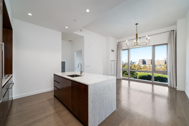 kitchen with an island with sink, sink, a chandelier, dark hardwood / wood-style flooring, and hanging light fixtures