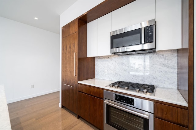 kitchen featuring white cabinetry, appliances with stainless steel finishes, tasteful backsplash, and light wood-type flooring