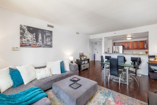 living room with visible vents, a textured ceiling, and wood finished floors