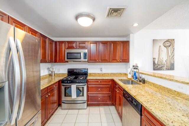 kitchen featuring a sink, stainless steel appliances, reddish brown cabinets, and visible vents