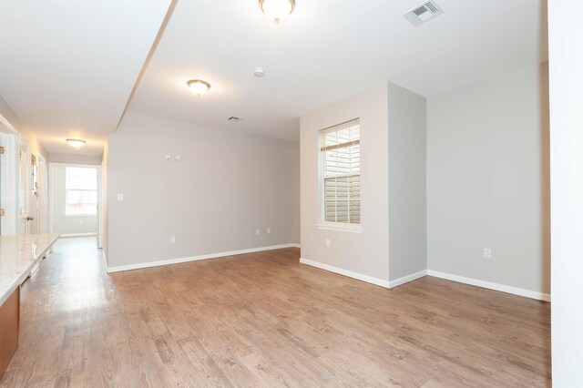 spare room with baseboards, visible vents, and light wood finished floors