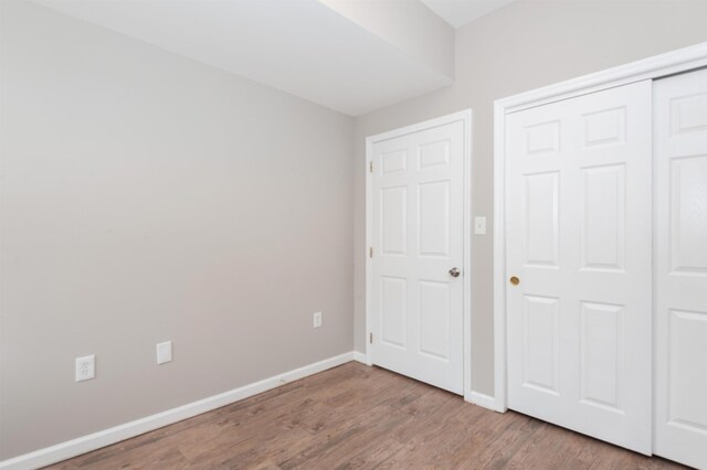 unfurnished bedroom with baseboards, a closet, and wood finished floors