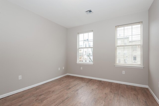 empty room featuring visible vents, baseboards, and wood finished floors