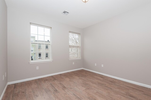 spare room with visible vents, baseboards, and wood finished floors