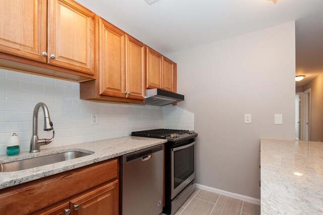 kitchen featuring a sink, appliances with stainless steel finishes, under cabinet range hood, and tasteful backsplash
