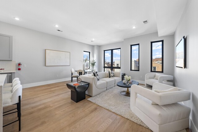 living room featuring baseboards, visible vents, light wood-style flooring, and recessed lighting