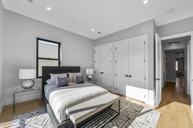 bedroom featuring multiple closets, recessed lighting, visible vents, and light wood-style flooring