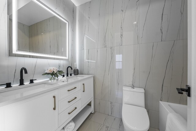 full bathroom with marble finish floor, double vanity, a sink, and toilet