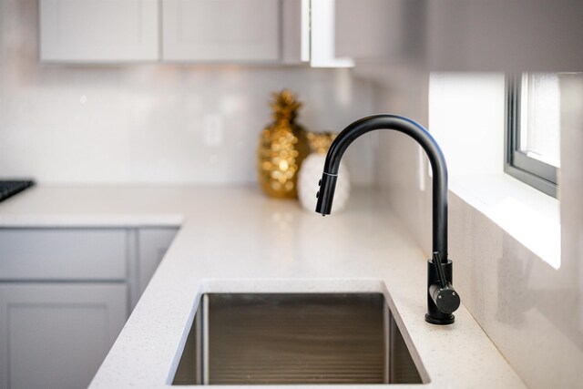 room details with light stone counters, a sink, and white cabinetry