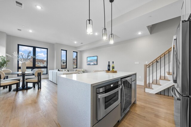 kitchen with wine cooler, visible vents, open floor plan, a center island, and pendant lighting