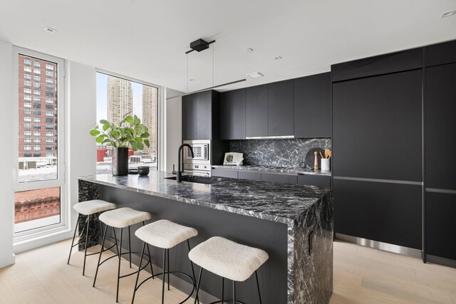 43 Provost St Unit 10O, Jersey City, NJ 07302 - kitchen with a sink, dark cabinetry, light wood finished floors, modern cabinets, and a kitchen bar