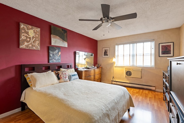 bedroom featuring baseboards, ceiling fan, wood finished floors, baseboard heating, and a textured ceiling