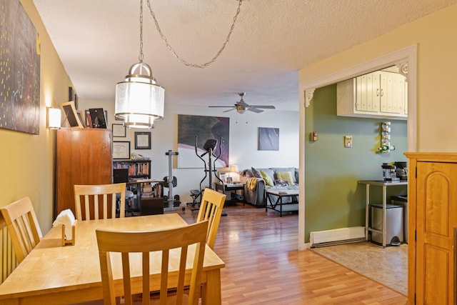 dining room with ceiling fan, a textured ceiling, wood finished floors, and baseboards