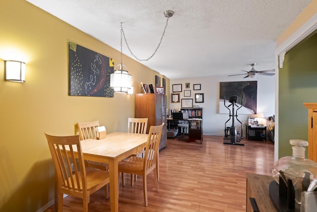 dining area with a textured ceiling, wood finished floors, and a ceiling fan