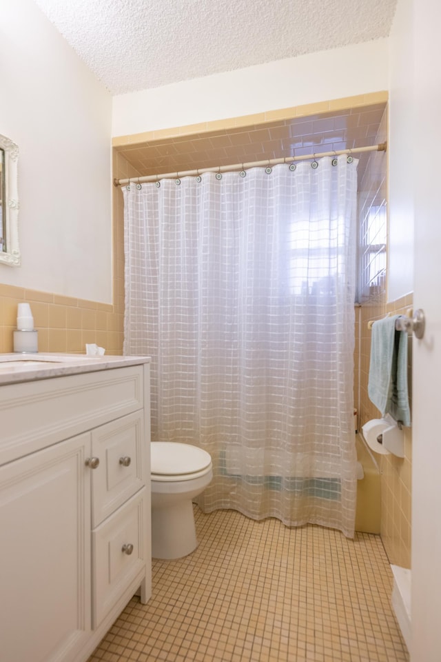 full bath featuring a shower with curtain, tile patterned flooring, a textured ceiling, and tile walls