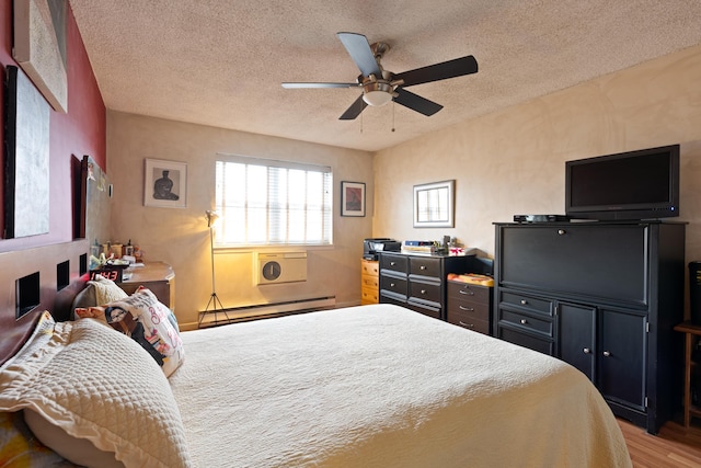 bedroom with a ceiling fan, a baseboard heating unit, a textured ceiling, and wood finished floors