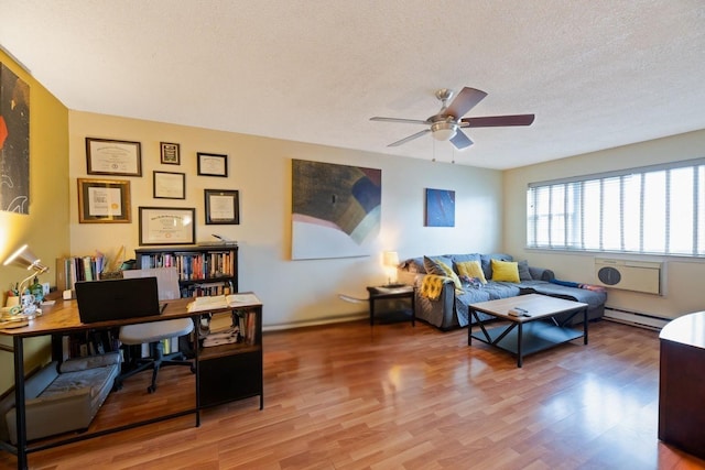 living room with a ceiling fan, a textured ceiling, a baseboard heating unit, and wood finished floors