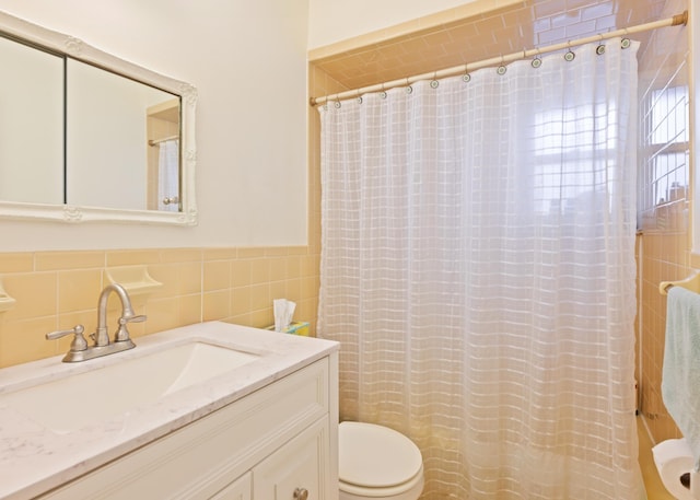 bathroom featuring a wainscoted wall, tile walls, toilet, and vanity