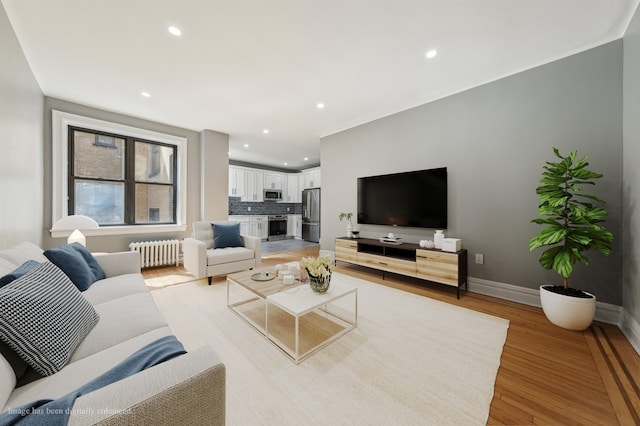 living room with radiator, light wood finished floors, baseboards, and recessed lighting