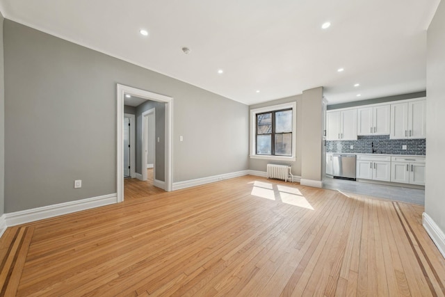 unfurnished living room with baseboards, light wood finished floors, recessed lighting, and radiator