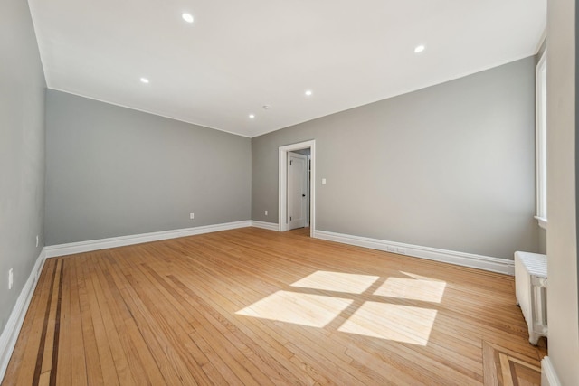 empty room featuring recessed lighting, baseboards, and light wood finished floors