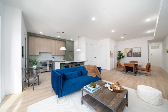 living area featuring baseboards, recessed lighting, and light wood-type flooring
