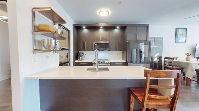 kitchen featuring a breakfast bar, sink, wood-type flooring, kitchen peninsula, and stainless steel appliances