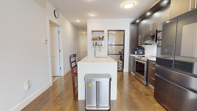 kitchen featuring light hardwood / wood-style floors, sink, stainless steel appliances, and an island with sink