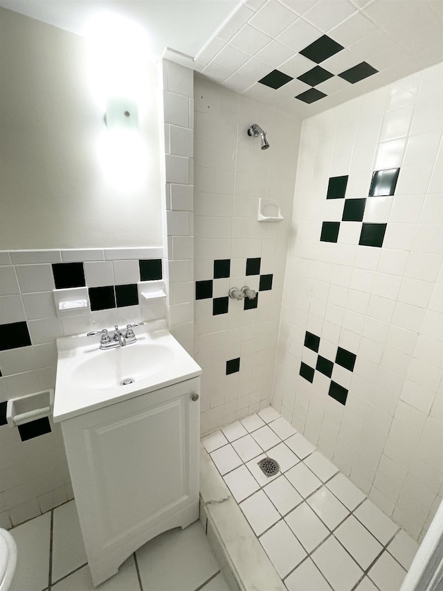 bathroom featuring tiled shower, vanity, and tile walls