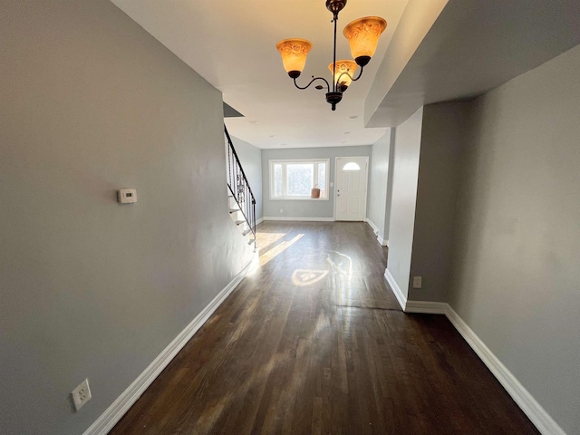 interior space featuring a chandelier, dark wood-style flooring, baseboards, and stairs