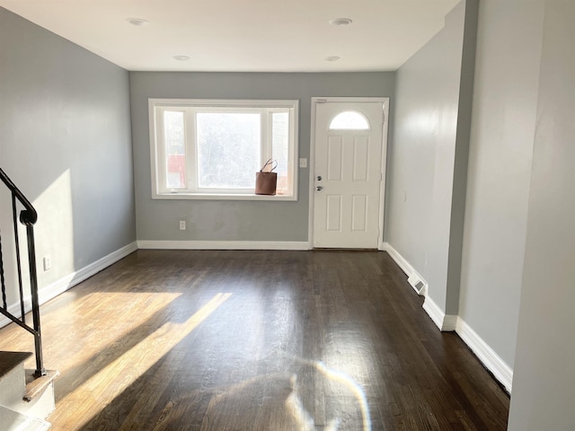 foyer entrance featuring dark wood-style floors, visible vents, and baseboards