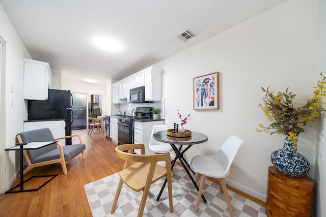 dining area featuring baseboards, visible vents, and light wood finished floors