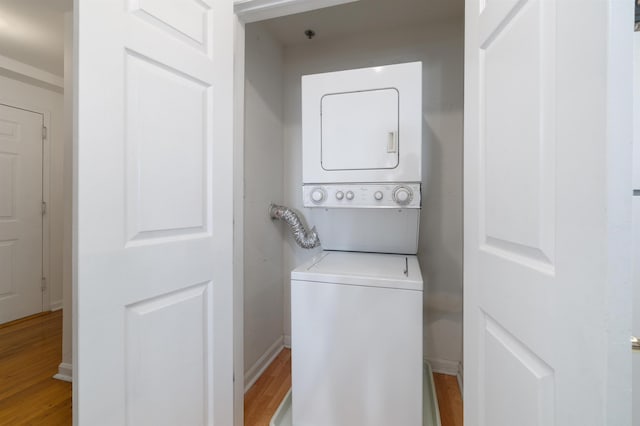 washroom with stacked washer / drying machine and light hardwood / wood-style floors