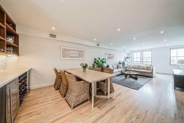 dining area featuring recessed lighting, baseboards, light wood finished floors, and beverage cooler
