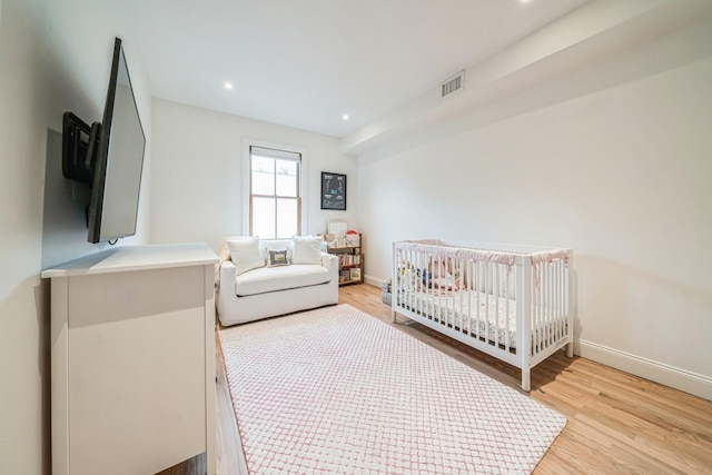 bedroom featuring visible vents, light wood-style flooring, and baseboards