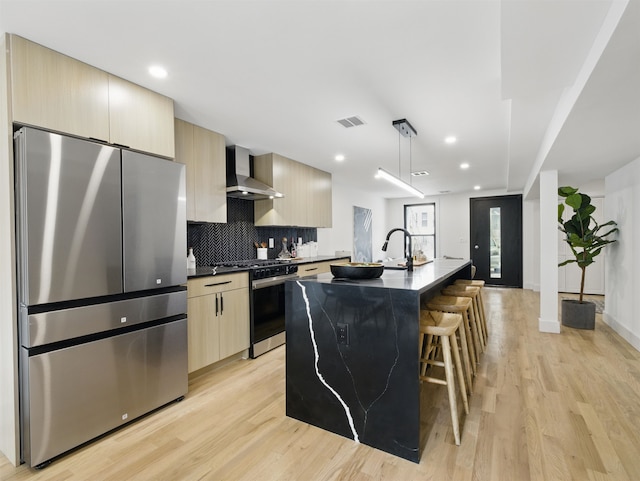 63 Jefferson Ave Unit 1, Jersey City, NJ 07307 - kitchen featuring appliances with stainless steel finishes, wall chimney exhaust hood, modern cabinets, light wood-type flooring, and a kitchen island with sink