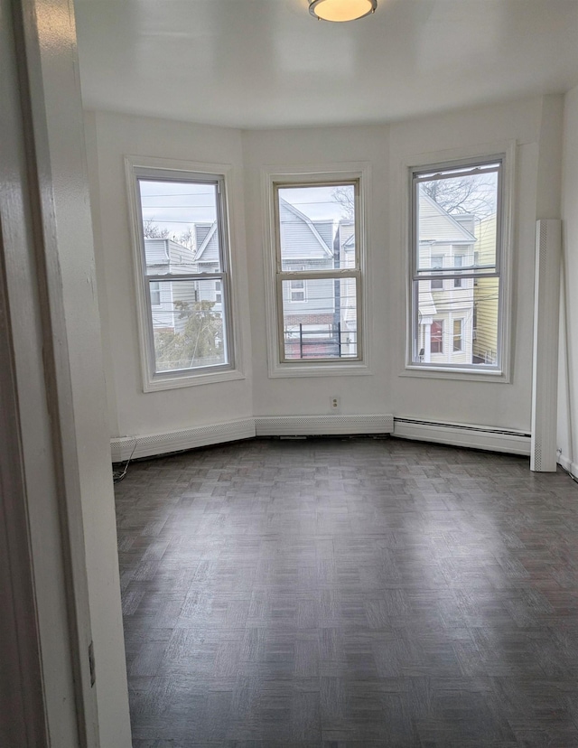 unfurnished room with a baseboard heating unit and plenty of natural light