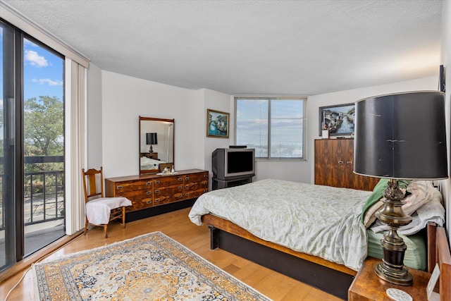 401 Harmon Cv, Secaucus, NJ 07094 - bedroom featuring access to exterior, wood finished floors, expansive windows, and a textured ceiling