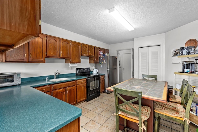 401 Harmon Cv, Secaucus, NJ 07094 - kitchen featuring black electric range, freestanding refrigerator, a textured ceiling, light tile patterned floors, and brown cabinetry