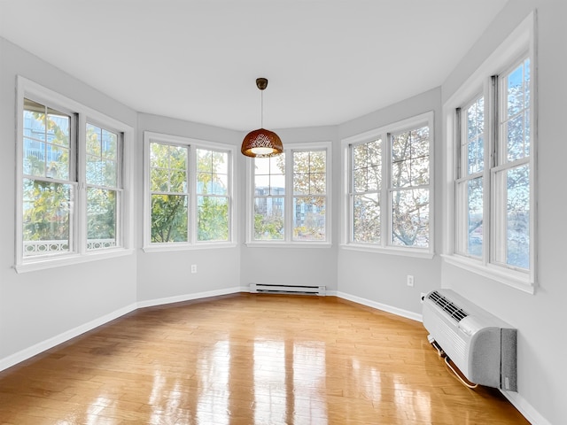 unfurnished sunroom featuring a wall mounted AC, a baseboard radiator, and a healthy amount of sunlight