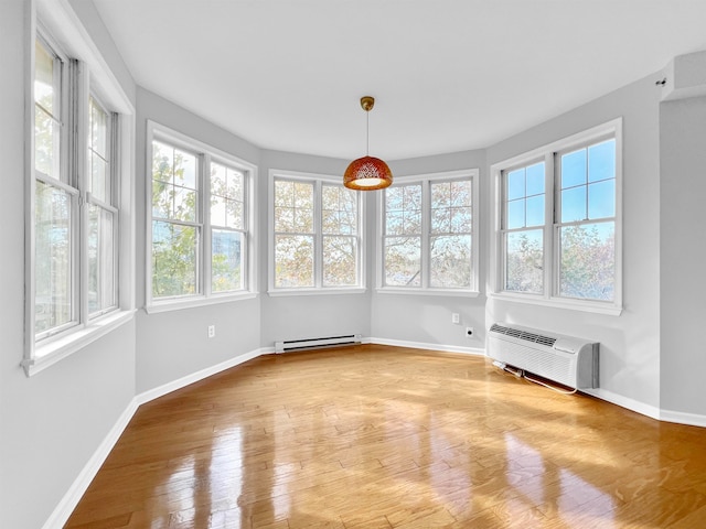 unfurnished sunroom with a baseboard heating unit, a wall unit AC, and plenty of natural light